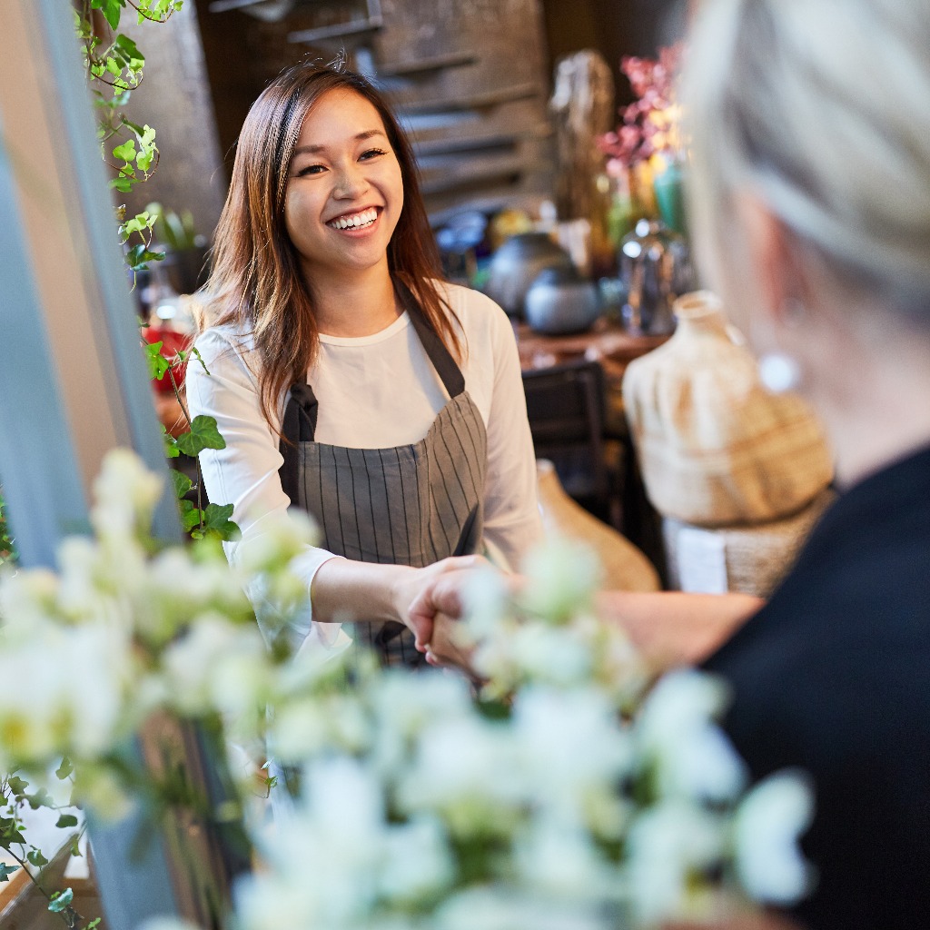 Florist welcomes customer with handshake in flower shop